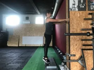 Eccentric calf drop – stanie przodostopiem na stepie, ręce oparte o ścianę